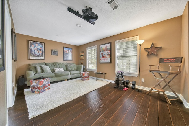 living area with dark wood-style floors, a textured ceiling, visible vents, and baseboards