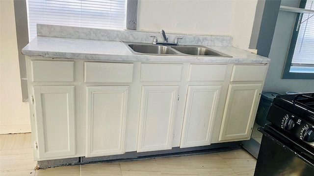 kitchen with white cabinets, black electric range oven, and sink