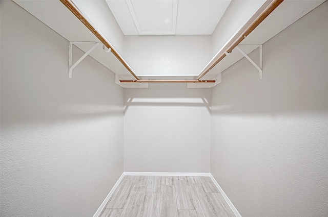 walk in closet with light hardwood / wood-style floors