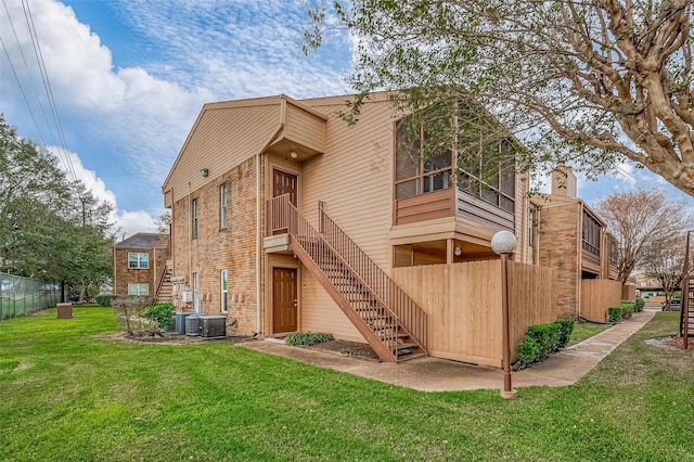 rear view of property with a yard and central AC