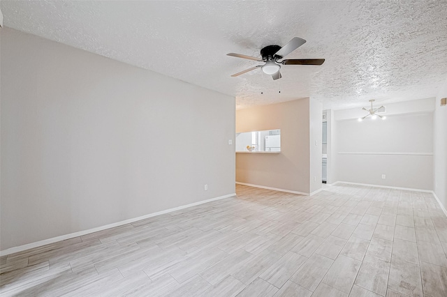 unfurnished room featuring a textured ceiling and ceiling fan with notable chandelier