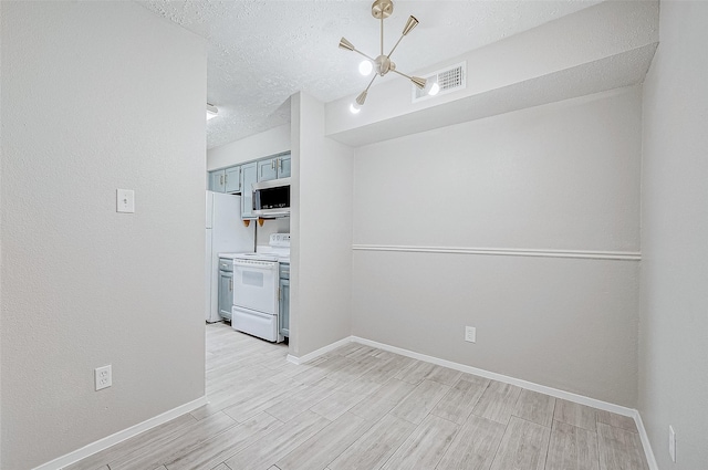 kitchen featuring a textured ceiling, white appliances, and a notable chandelier