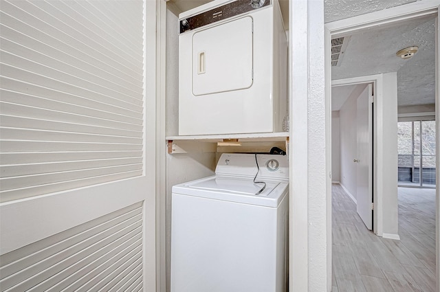 laundry area featuring stacked washing maching and dryer and light hardwood / wood-style floors