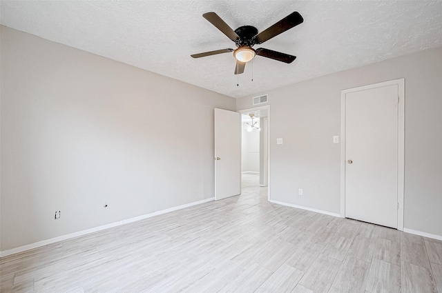 empty room with ceiling fan, light hardwood / wood-style floors, and a textured ceiling