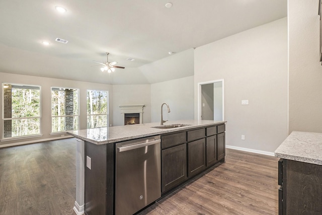 kitchen featuring dark brown cabinetry, sink, stainless steel dishwasher, vaulted ceiling, and a kitchen island with sink