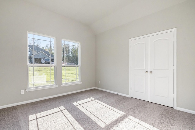 unfurnished bedroom featuring carpet, lofted ceiling, and a closet