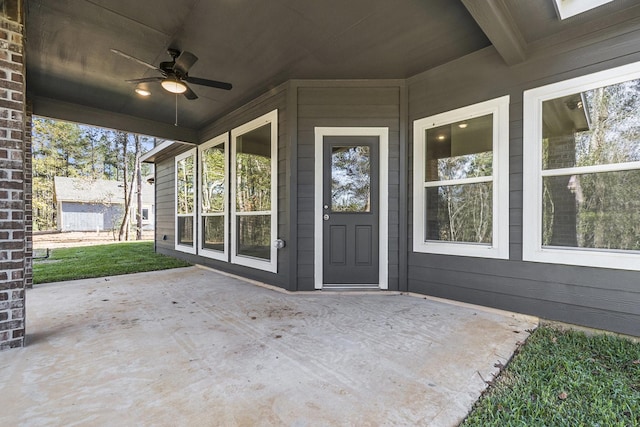 view of exterior entry featuring ceiling fan and a patio