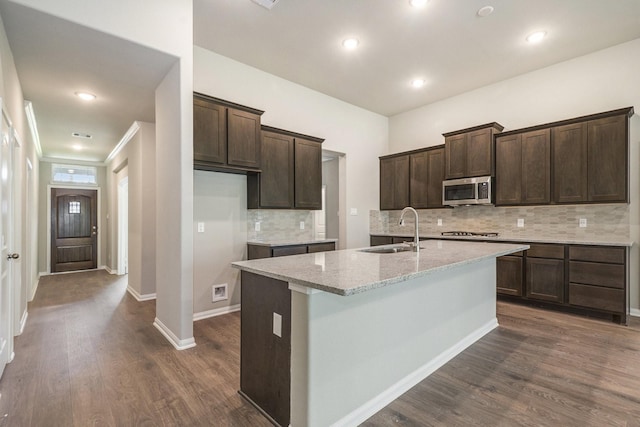 kitchen with appliances with stainless steel finishes, a center island with sink, dark wood-type flooring, and sink