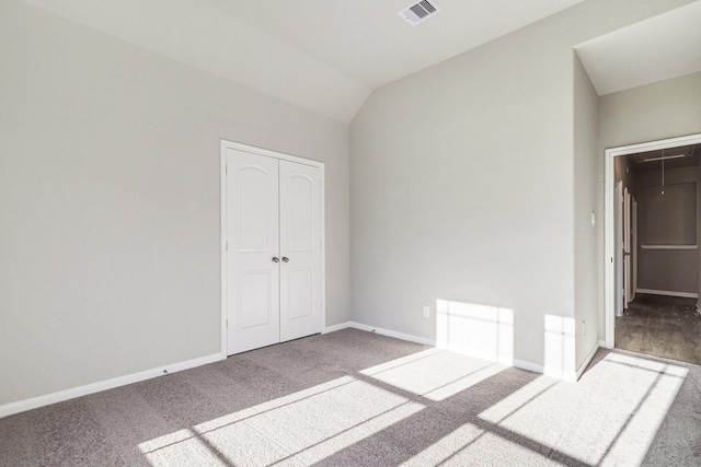 unfurnished bedroom with lofted ceiling, carpet floors, and a closet