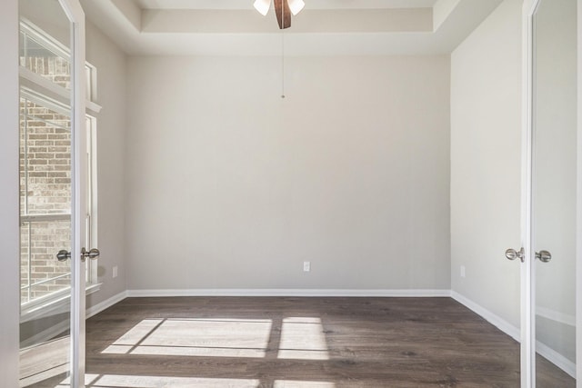 empty room featuring a tray ceiling, ceiling fan, french doors, and dark hardwood / wood-style floors