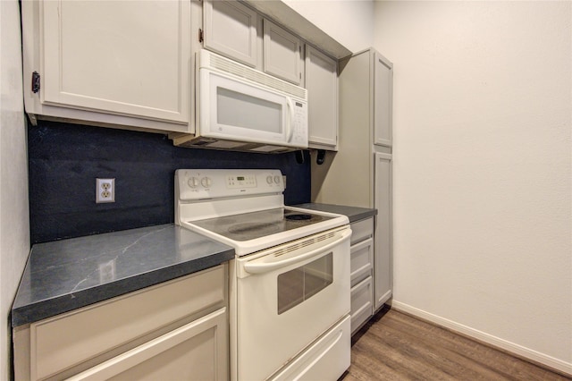 kitchen featuring white appliances, tasteful backsplash, white cabinetry, and dark hardwood / wood-style floors