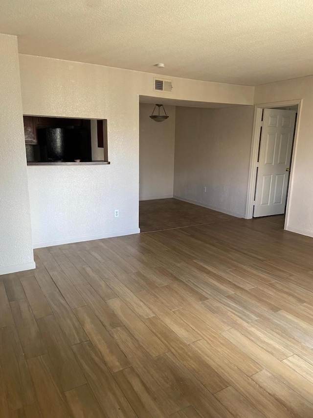 unfurnished room with hardwood / wood-style floors and a textured ceiling