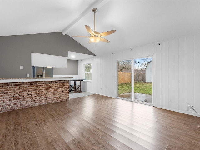 unfurnished living room featuring vaulted ceiling with beams, ceiling fan, and wood-type flooring