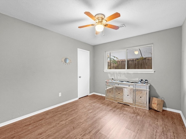 interior space with ceiling fan, wood-type flooring, and a textured ceiling