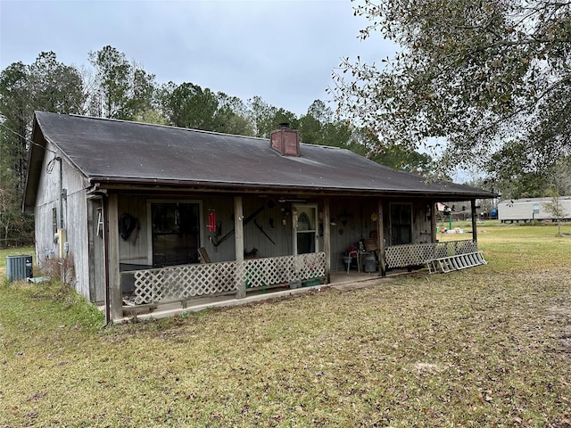 rear view of property featuring covered porch, a yard, and central AC