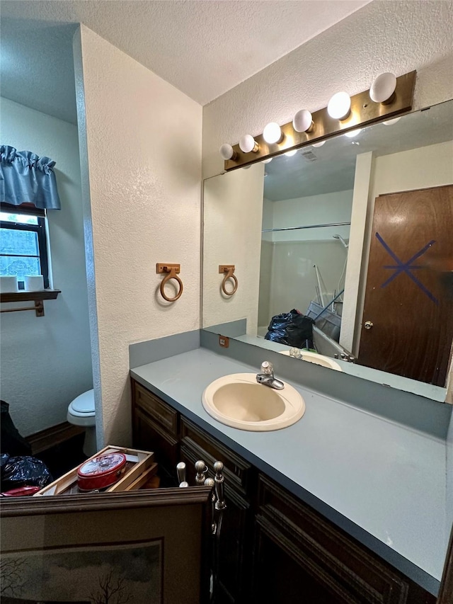 bathroom featuring vanity, a textured ceiling, toilet, and walk in shower