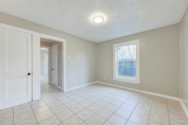 tiled empty room with a textured ceiling