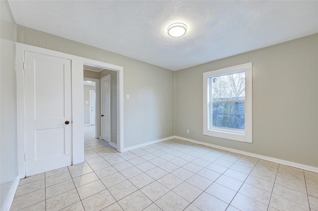 unfurnished room with light tile patterned flooring and a textured ceiling