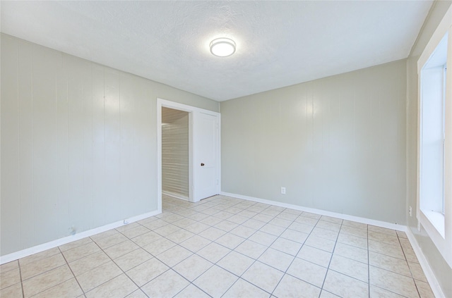 tiled spare room featuring wooden walls and a textured ceiling