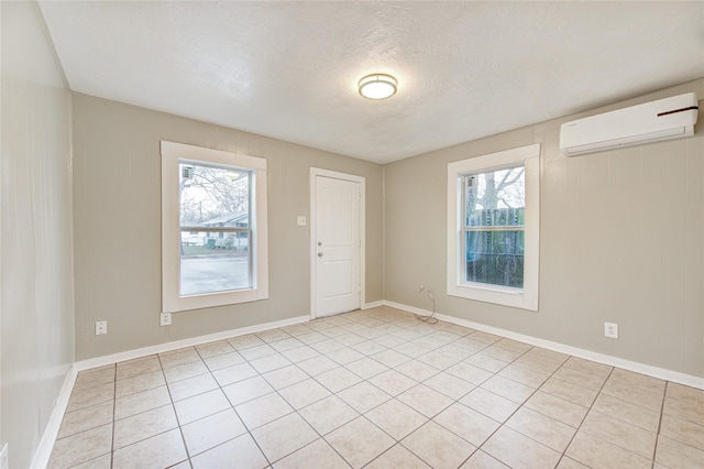 tiled empty room with a wealth of natural light, a textured ceiling, and a wall mounted AC