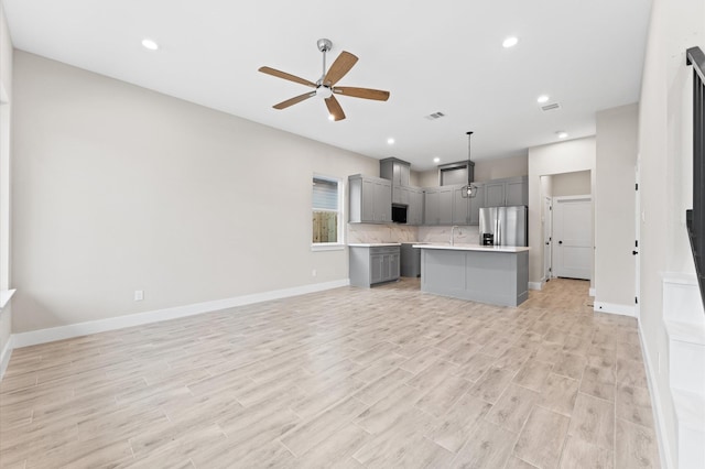 kitchen featuring gray cabinetry, ceiling fan, hanging light fixtures, stainless steel refrigerator with ice dispenser, and a kitchen island