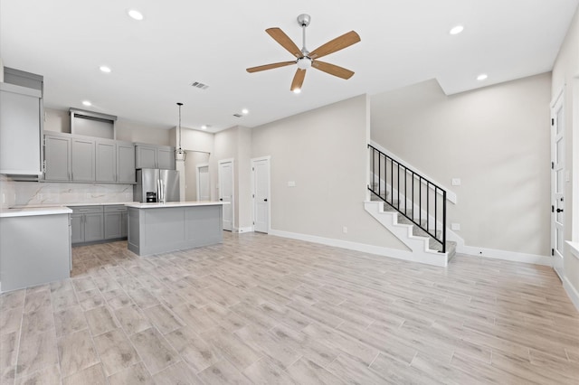 kitchen featuring gray cabinetry, ceiling fan, decorative light fixtures, a kitchen island, and stainless steel fridge with ice dispenser