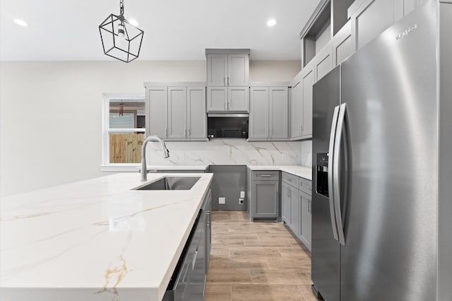 kitchen featuring light stone countertops, sink, decorative light fixtures, decorative backsplash, and appliances with stainless steel finishes