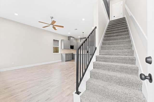 stairs with ceiling fan and hardwood / wood-style floors