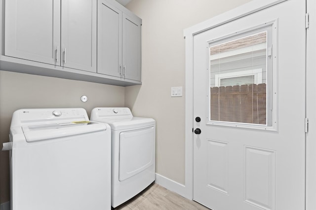 washroom with cabinets, light hardwood / wood-style flooring, and washing machine and clothes dryer