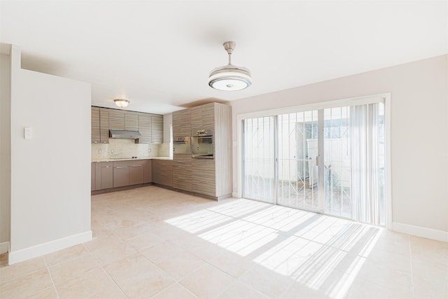 kitchen featuring light tile patterned floors, tasteful backsplash, oven, and range hood