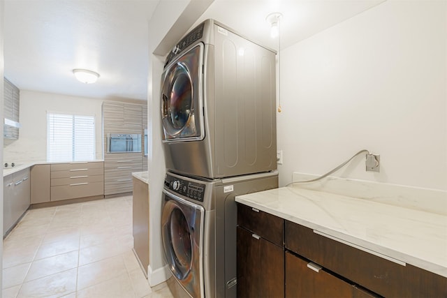 laundry room with cabinets and stacked washer / dryer