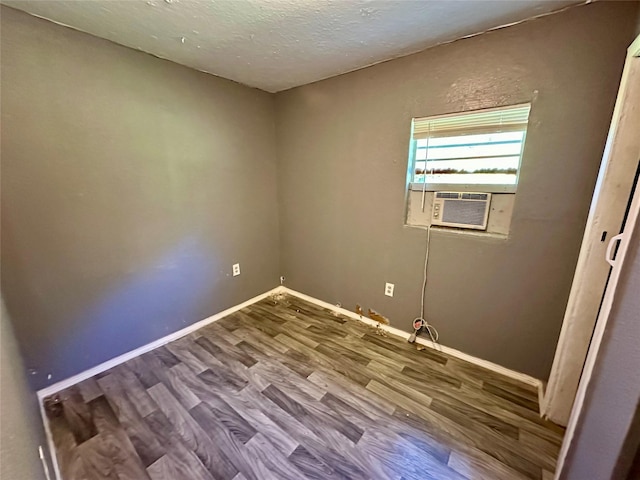 empty room with a textured ceiling, hardwood / wood-style flooring, and cooling unit