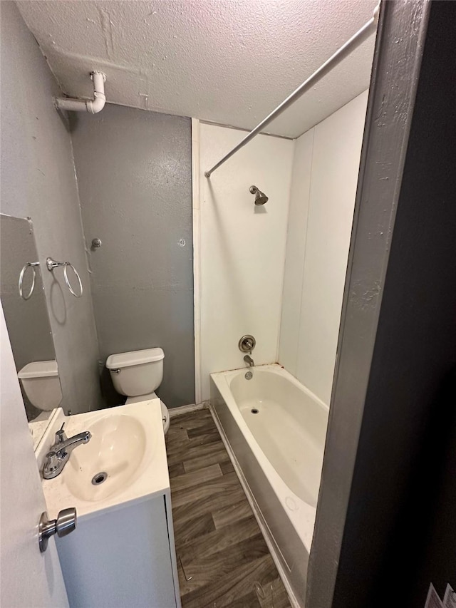 full bathroom with tub / shower combination, hardwood / wood-style floors, a textured ceiling, toilet, and vanity