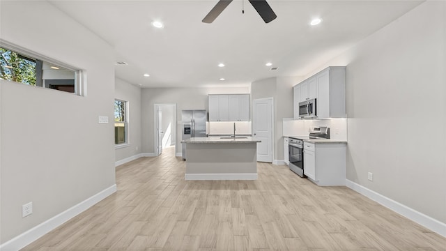 kitchen featuring light stone counters, plenty of natural light, an island with sink, and appliances with stainless steel finishes