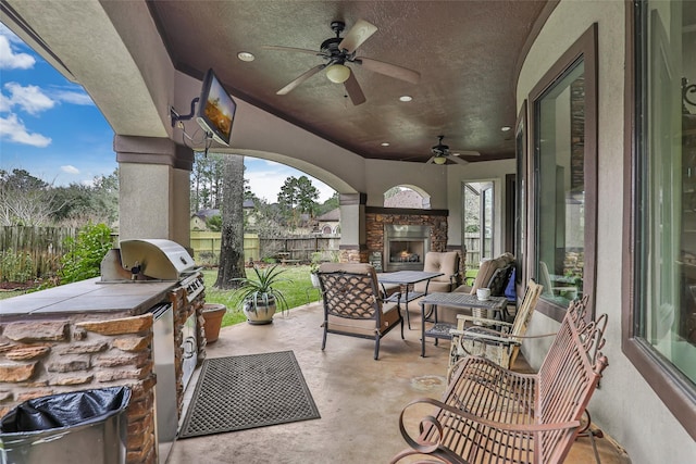 view of patio with an outdoor stone fireplace, an outdoor kitchen, and ceiling fan