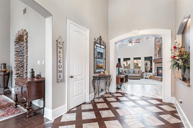 foyer with a towering ceiling, a stone fireplace, and ceiling fan