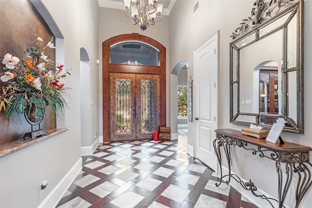 entrance foyer with french doors, a chandelier, a high ceiling, and ornamental molding