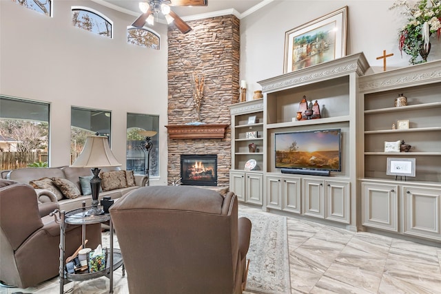 living room featuring ceiling fan, a fireplace, a high ceiling, and ornamental molding