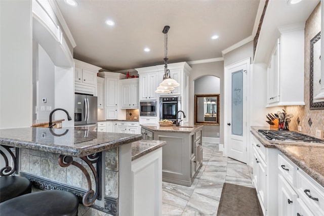 kitchen featuring appliances with stainless steel finishes, backsplash, an island with sink, and a breakfast bar area