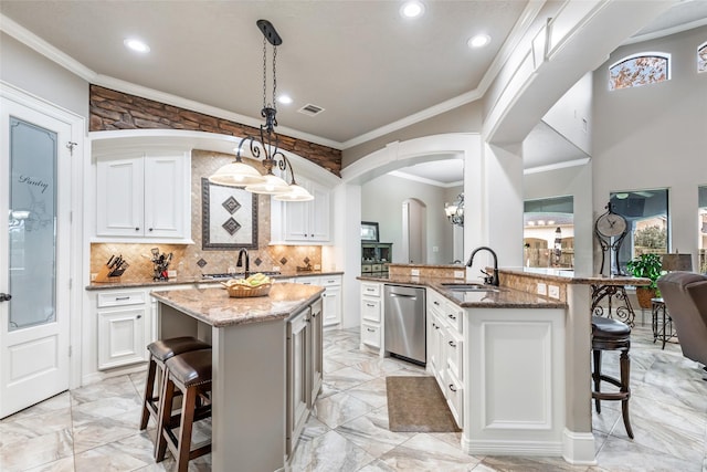 kitchen with kitchen peninsula, sink, white cabinetry, hanging light fixtures, and a breakfast bar area