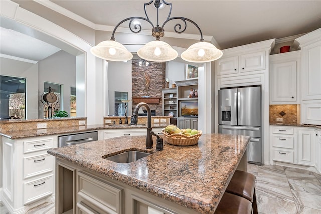 kitchen featuring stone counters, sink, an island with sink, and appliances with stainless steel finishes