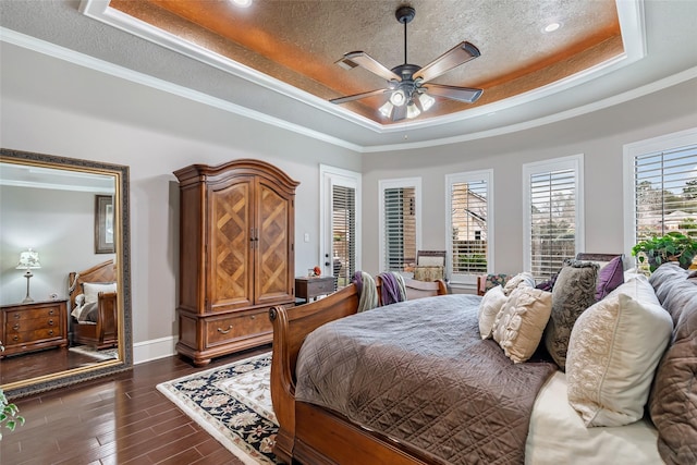 bedroom featuring ceiling fan, dark wood-type flooring, a raised ceiling, a textured ceiling, and ornamental molding