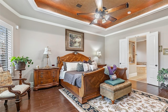 bedroom featuring a tray ceiling, ensuite bath, ceiling fan, and ornamental molding