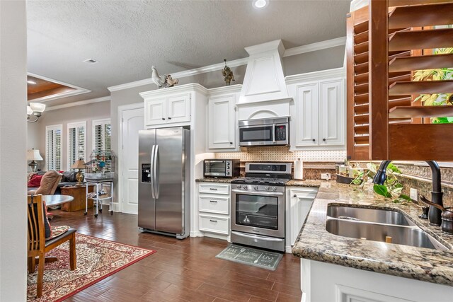 kitchen featuring light stone countertops, appliances with stainless steel finishes, backsplash, sink, and white cabinetry