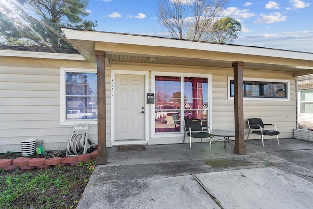 entrance to property with a porch and a patio