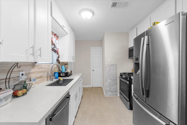 kitchen featuring sink, decorative backsplash, a textured ceiling, white cabinetry, and stainless steel appliances