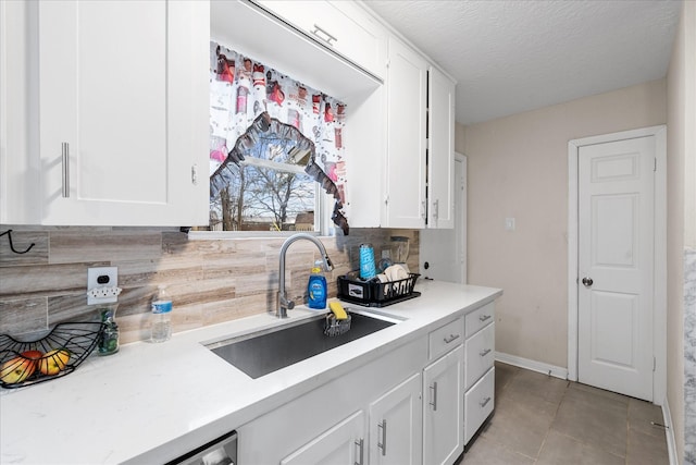 kitchen featuring sink, light tile patterned floors, backsplash, a textured ceiling, and white cabinets