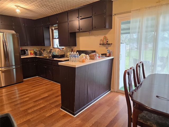 kitchen with kitchen peninsula, stainless steel fridge, and light hardwood / wood-style floors