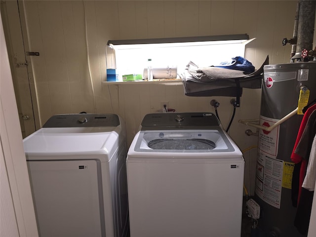 laundry room featuring washing machine and clothes dryer, water heater, and wood walls