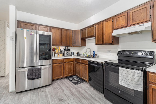 kitchen with sink, a textured ceiling, light wood-type flooring, and black appliances